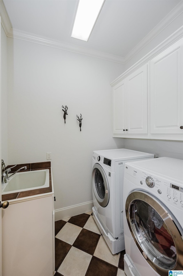 laundry room featuring dark floors, crown molding, cabinet space, a sink, and independent washer and dryer