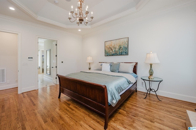 bedroom with light wood-type flooring, visible vents, a tray ceiling, and ornamental molding