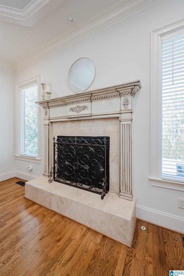 interior details featuring ornamental molding, wood finished floors, a high end fireplace, and baseboards