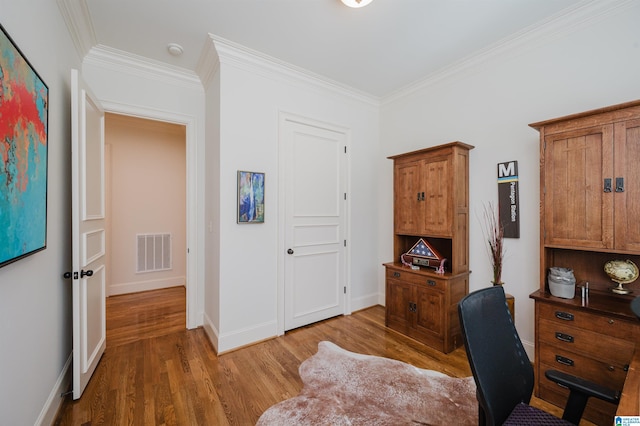 office area with ornamental molding, wood finished floors, visible vents, and baseboards