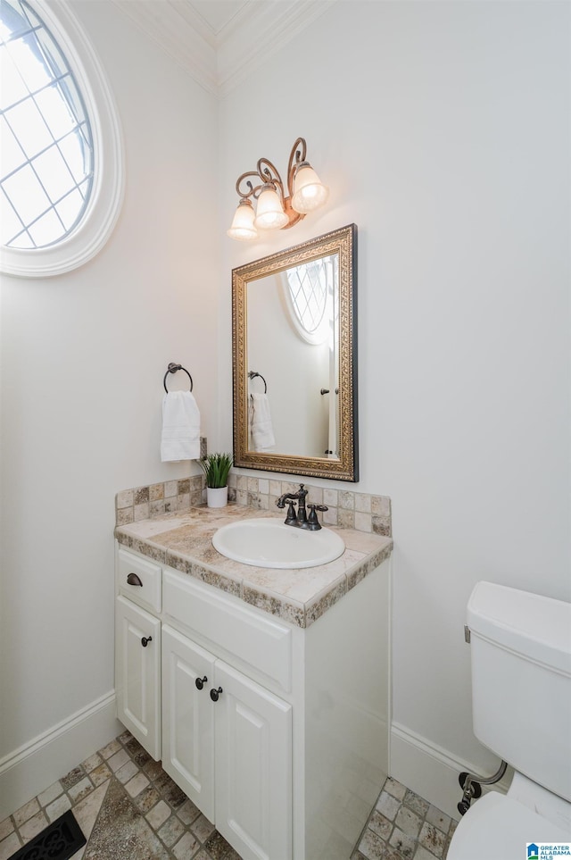 bathroom featuring toilet, baseboards, crown molding, and vanity