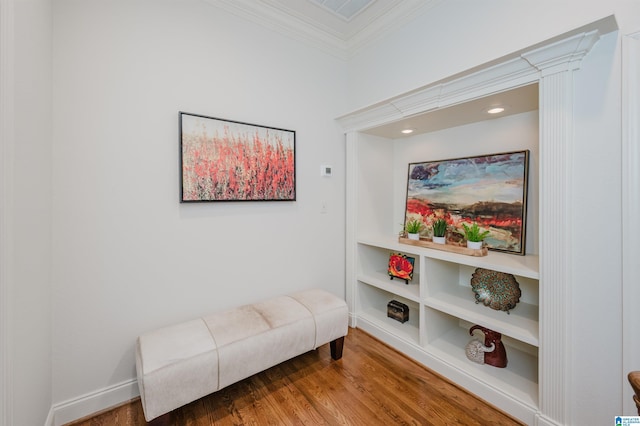 living area featuring built in shelves, crown molding, visible vents, wood finished floors, and baseboards