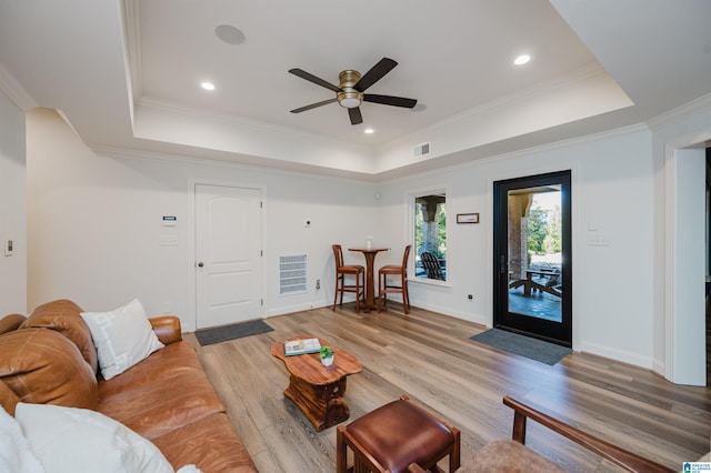 living area featuring light wood-style floors, ornamental molding, and a raised ceiling