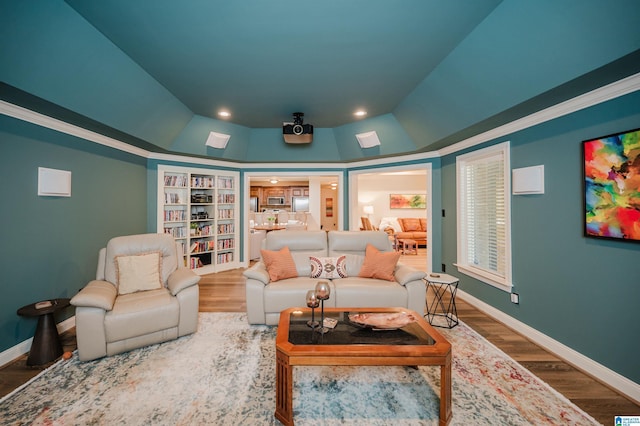 interior space featuring vaulted ceiling, a tray ceiling, wood finished floors, and baseboards