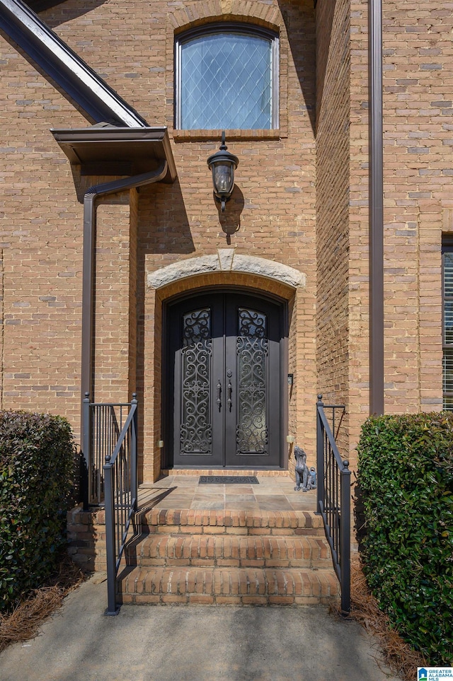 entrance to property featuring french doors and brick siding