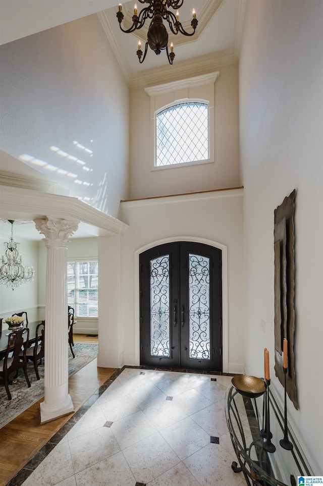 entryway featuring ornate columns, french doors, and an inviting chandelier