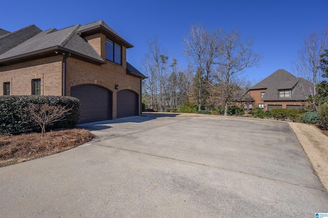 view of home's exterior featuring a garage, concrete driveway, brick siding, and a shingled roof