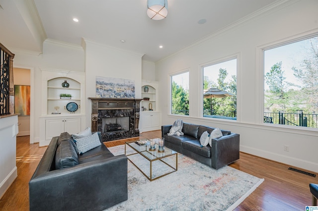 living area with built in shelves, a fireplace, baseboards, and wood finished floors