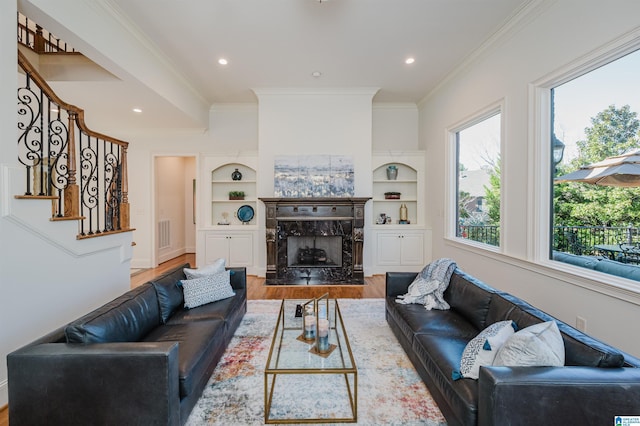 living room with crown molding, visible vents, stairway, a premium fireplace, and wood finished floors