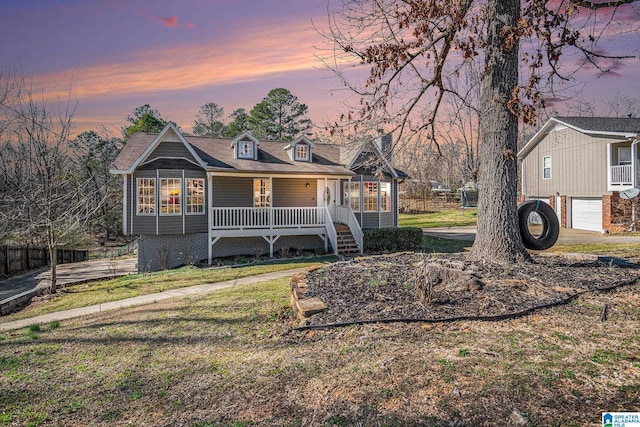 view of front of home with covered porch, a yard, driveway, and a garage