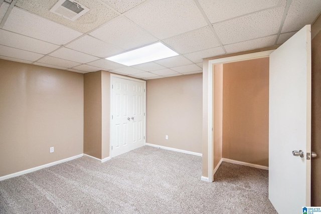 finished basement with carpet, visible vents, a drop ceiling, and baseboards