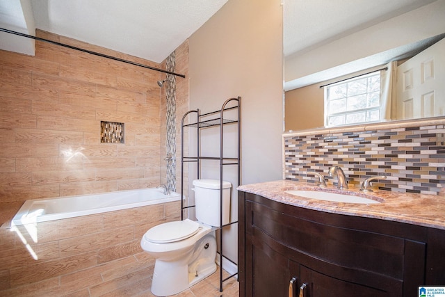 full bathroom with decorative backsplash, toilet, wood finished floors, tiled shower / bath combo, and vanity