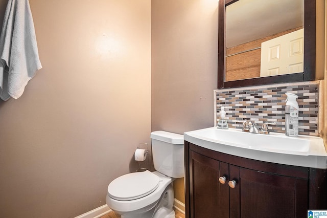 bathroom with baseboards, toilet, vanity, and decorative backsplash