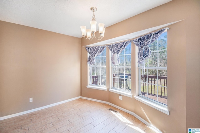 unfurnished dining area with a chandelier, a textured ceiling, visible vents, baseboards, and light wood-type flooring