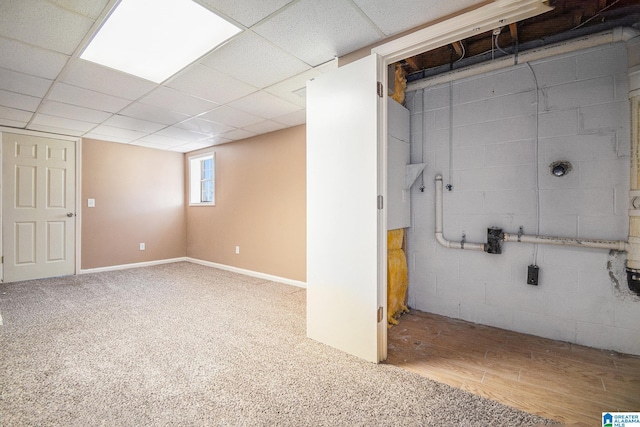 below grade area with baseboards, a drop ceiling, and wood finished floors