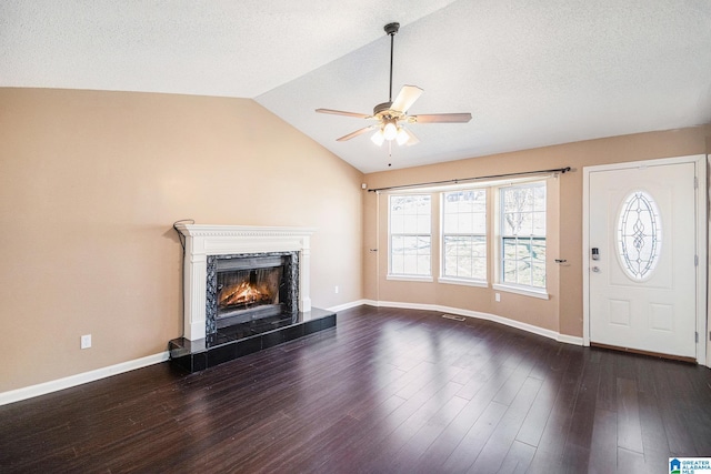 unfurnished living room featuring wood finished floors, a high end fireplace, baseboards, vaulted ceiling, and a ceiling fan