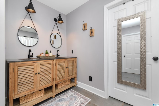 full bathroom featuring double vanity, baseboards, and a sink