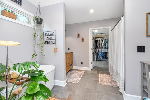 bathroom featuring recessed lighting, a freestanding bath, and baseboards