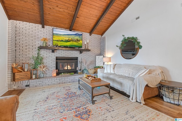 living area featuring visible vents, wooden ceiling, wood finished floors, vaulted ceiling with beams, and a brick fireplace