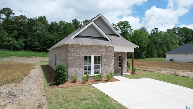 view of front of home featuring a front yard, brick siding, and roof with shingles