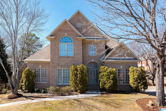 traditional-style home with a front yard and brick siding