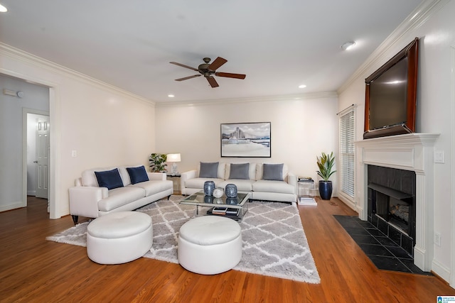 living room with crown molding, ceiling fan, wood finished floors, and a tile fireplace