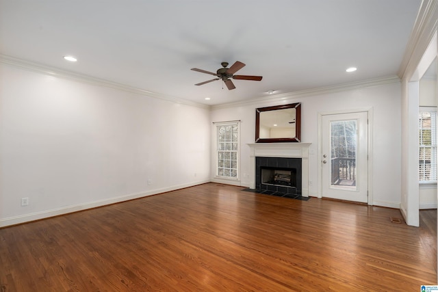 unfurnished living room featuring plenty of natural light, ornamental molding, wood finished floors, and a tile fireplace