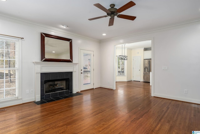 unfurnished living room with a wealth of natural light, a tiled fireplace, and wood finished floors