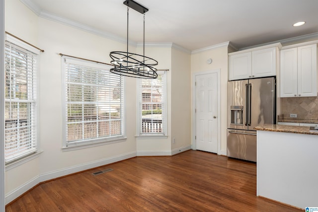 unfurnished dining area featuring a healthy amount of sunlight, visible vents, dark wood finished floors, and ornamental molding