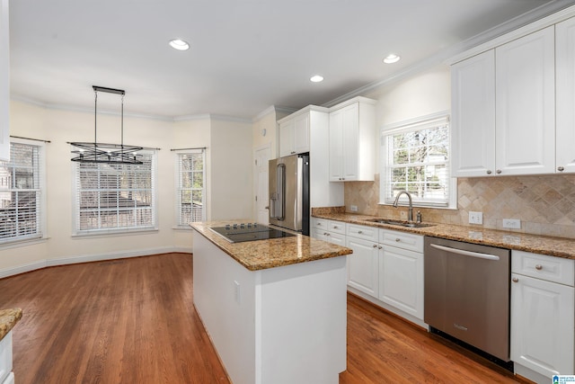 kitchen with tasteful backsplash, appliances with stainless steel finishes, ornamental molding, a sink, and a kitchen island