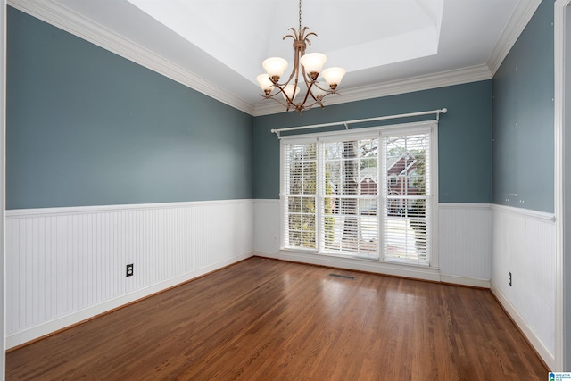 unfurnished room with a chandelier, wood finished floors, visible vents, wainscoting, and a raised ceiling