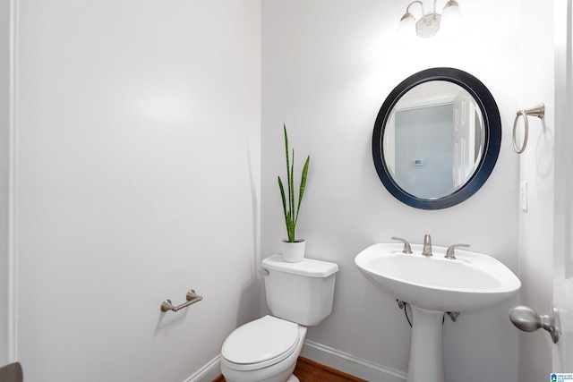 half bath with baseboards and toilet