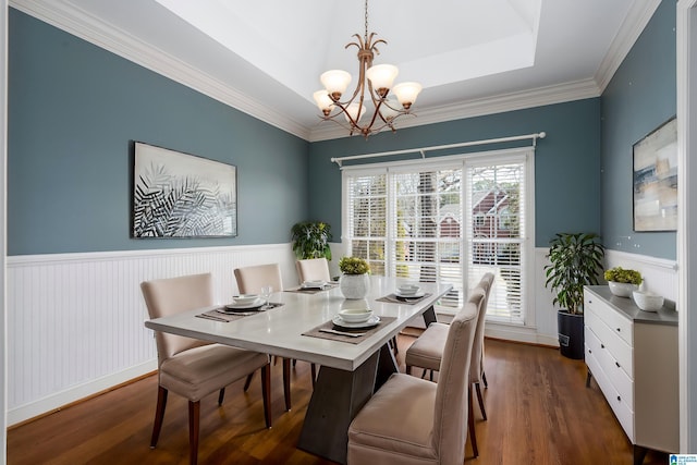 dining room featuring a wainscoted wall, a chandelier, a raised ceiling, and dark wood-type flooring