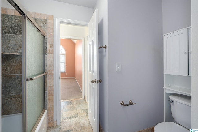 full bath featuring baseboards, combined bath / shower with glass door, toilet, and stone tile floors