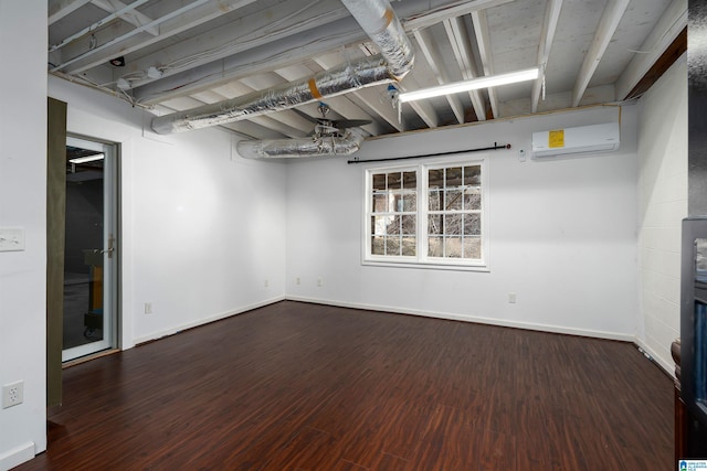 basement with an AC wall unit, baseboards, and wood finished floors