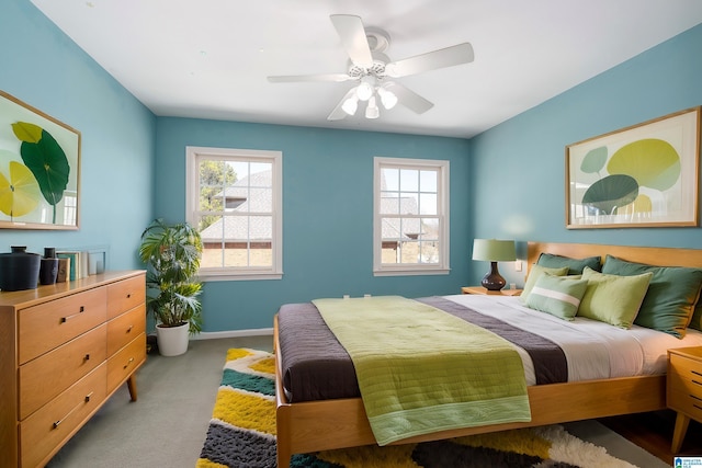 bedroom featuring carpet floors, multiple windows, a ceiling fan, and baseboards