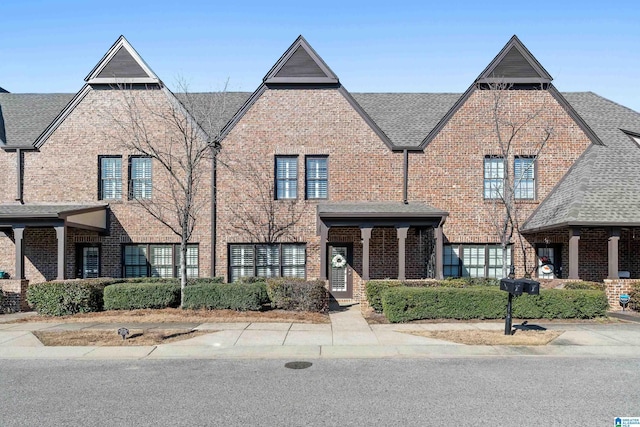 view of front of house with brick siding and roof with shingles