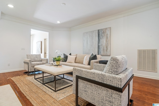 living area featuring baseboards, visible vents, wood finished floors, and ornamental molding