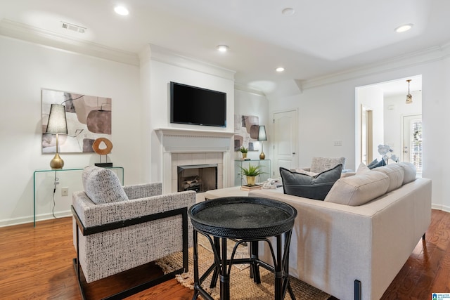 living room featuring a fireplace, visible vents, wood finished floors, and ornamental molding