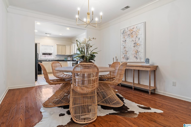 dining room with baseboards, light wood-style flooring, visible vents, and crown molding