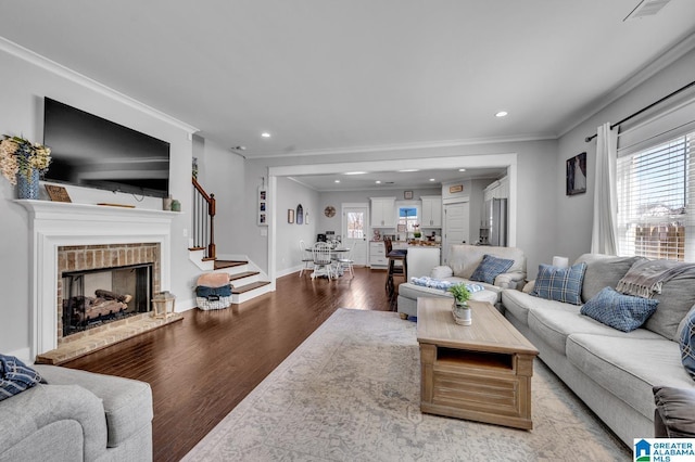 living area with a brick fireplace, light wood-style flooring, ornamental molding, and a wealth of natural light