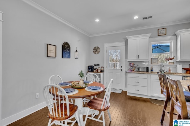 dining room featuring ornamental molding, dark wood-style flooring, visible vents, and baseboards