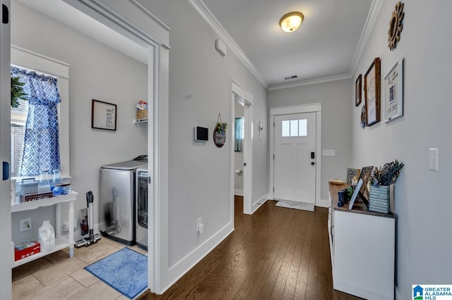 foyer entrance with visible vents, baseboards, light wood-style flooring, ornamental molding, and independent washer and dryer