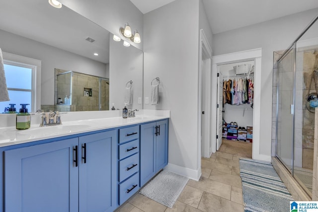 bathroom featuring a walk in closet, a sink, a shower stall, and tile patterned floors