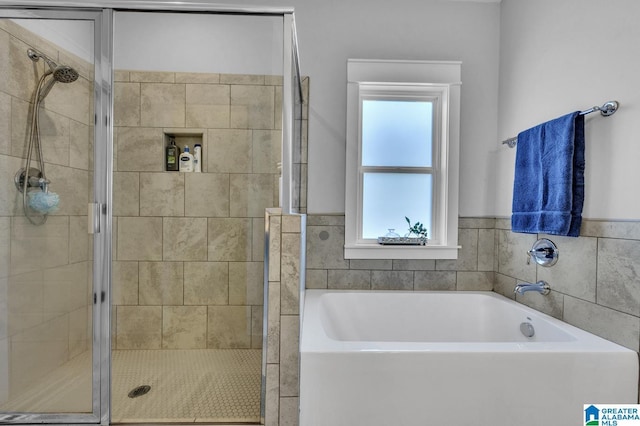 bathroom featuring a shower stall and a bath