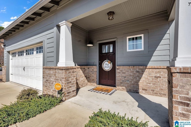 property entrance featuring concrete driveway, brick siding, and an attached garage