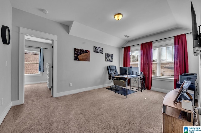 office space with visible vents, baseboards, vaulted ceiling, and light colored carpet