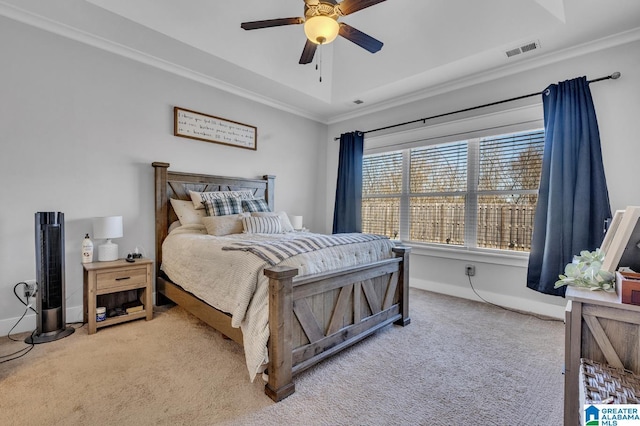 bedroom featuring light carpet, baseboards, visible vents, a tray ceiling, and crown molding