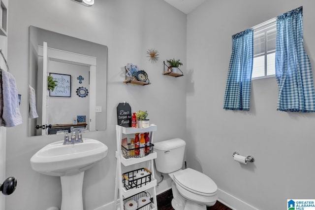 bathroom featuring toilet, baseboards, and a sink