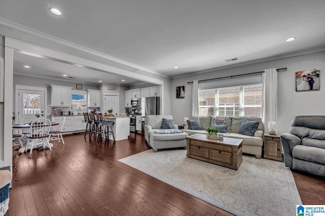 living room featuring dark wood-style floors, visible vents, and ornamental molding